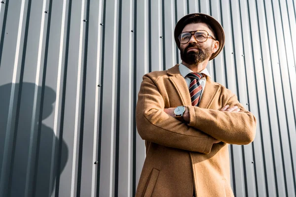 Adulto bello uomo d'affari in piedi con le braccia incrociate vicino al muro — Foto stock