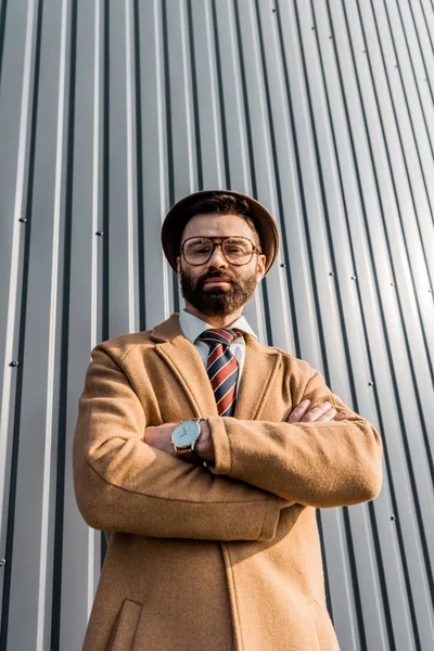 Vue en angle bas de l'homme d'affaires confiant debout avec les bras croisés — Photo de stock