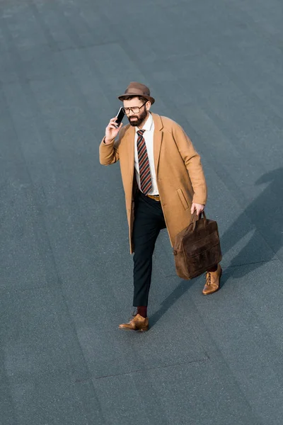 Bellissimo uomo d'affari con borsa che cammina e parla su smartphone — Foto stock