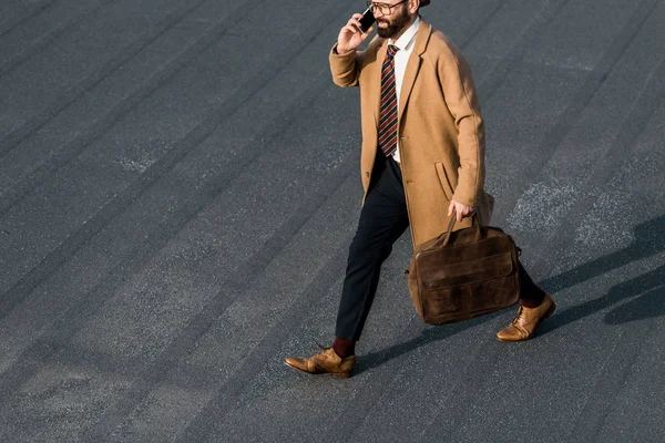 Vista recortada de hombre de negocios barbudo en gafas hablando en el teléfono inteligente - foto de stock