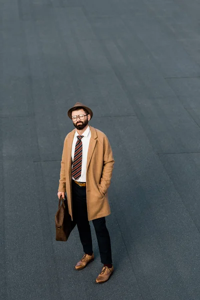 Adult businessman in formalwear and coat standing on grey roof — Stock Photo