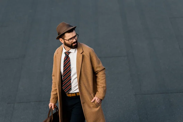 Adulto hombre de negocios en gafas y sombrero de pie con la mano en el bolsillo — Stock Photo