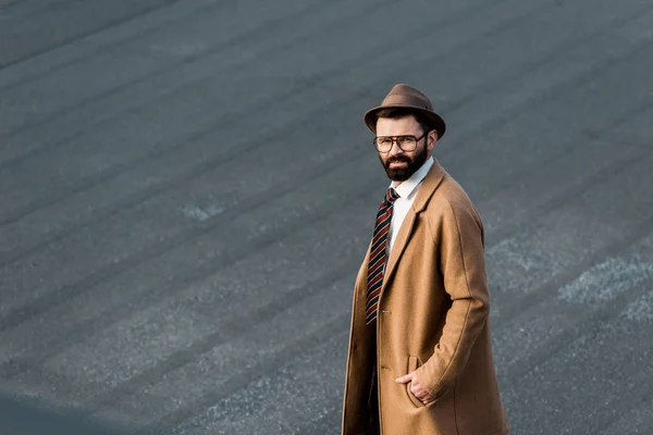 Homme d'affaires confiant dans des lunettes debout avec la main dans la poche et regardant la caméra — Photo de stock