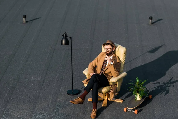 Adulte homme d'affaires reposant dans un fauteuil avec cigarette près de la lampe et plante sur panneau penny — Photo de stock