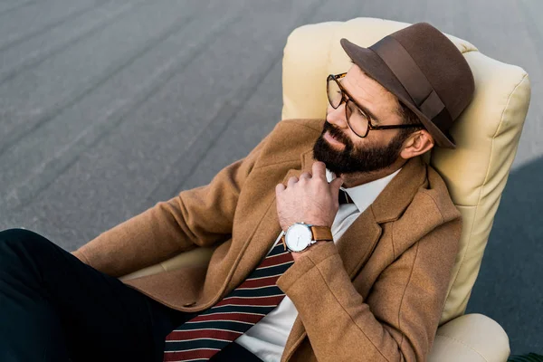 Pensativo hombre de negocios barbudo en gafas sentado en sillón - foto de stock