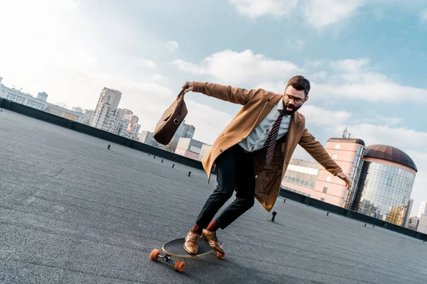 Animado empresário equitação no penny board com saco na mão — Fotografia de Stock