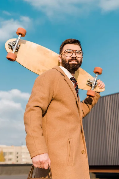 Smiling businessman in glasses holding penny board — Stock Photo
