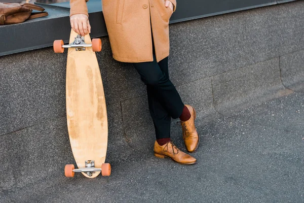 Recortado vista de hombre de negocios en abrigo celebración penny board - foto de stock