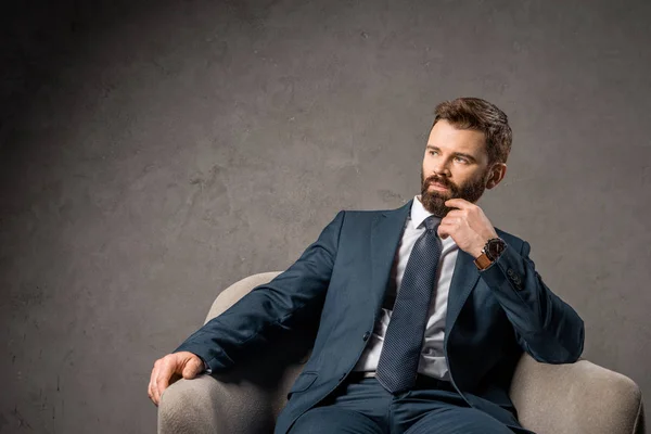 Pensativo hombre de negocios barbudo sentado en sillón - foto de stock