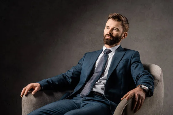 Hombre de negocios barbudo confiado descansando en sillón - foto de stock