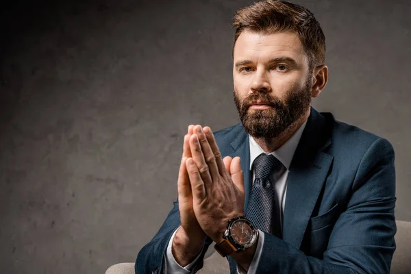 Primer plano del hombre de negocios barbudo sentado en sillón con las manos de oración - foto de stock