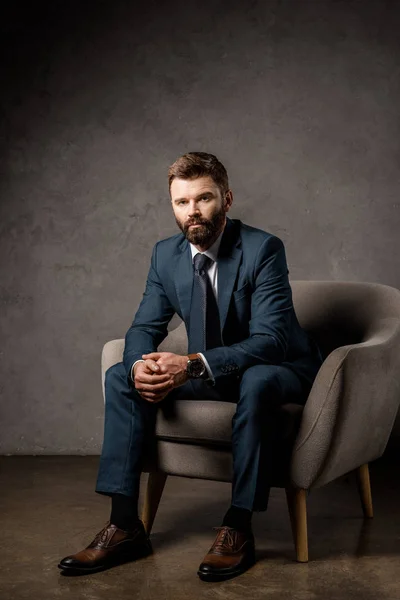 Guapo barbudo hombre de negocios sentado en sillón - foto de stock