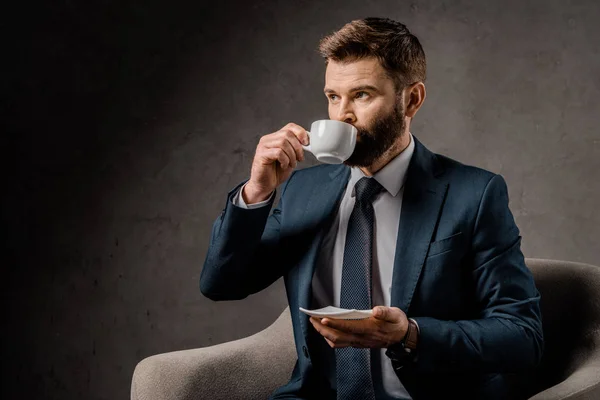 Uomo d'affari fiducioso bere caffè e tenere piattino — Foto stock