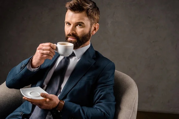 Homme d'affaires réussi à boire du café et soucoupe tenue — Photo de stock