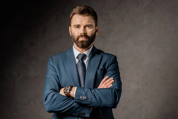 Handsome bearded businessman standing with crossed arms — Stock Photo
