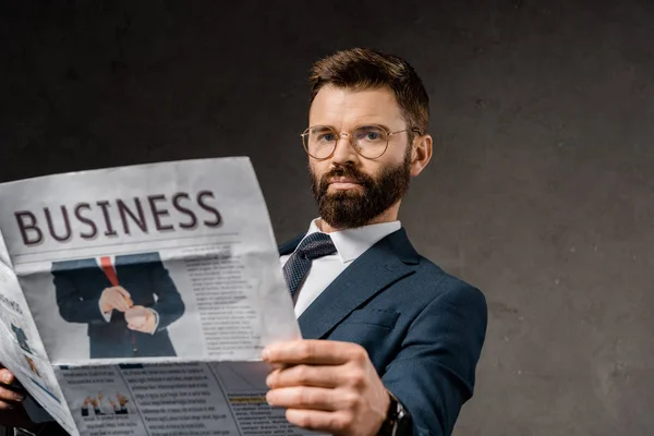 Bearded businessman in formalwear holding newspaper — Stock Photo