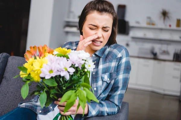 Jovem com espirros de alergia e segurando buquê de flores — Fotografia de Stock