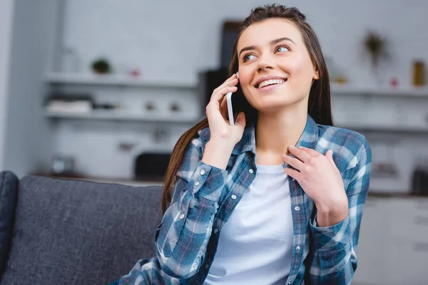 Щаслива молода жінка розмовляє по смартфону, сидячи вдома — стокове фото