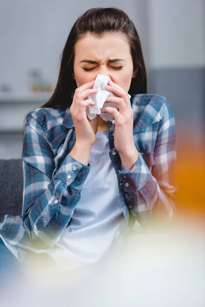 Selective focus of young woman with allergy blowing nose in facial tissue — Stock Photo