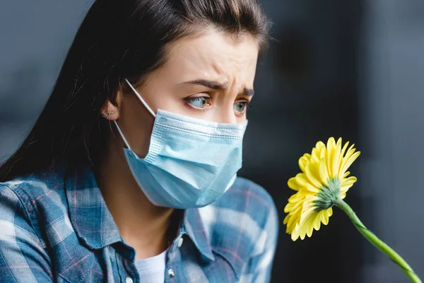 Mädchen mit Allergie trägt medizinische Maske und betrachtet Blume — Stockfoto