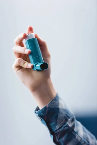 Vista parcial de cerca de una mujer joven que sostiene un inhalador de asma - foto de stock
