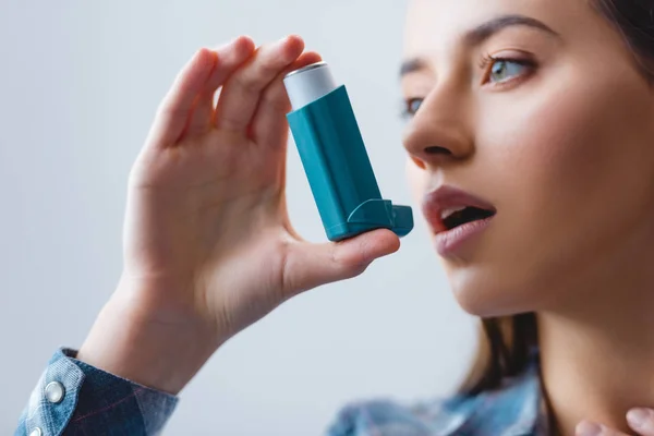 Vista de cerca de la mujer joven con asma usando inhalador - foto de stock