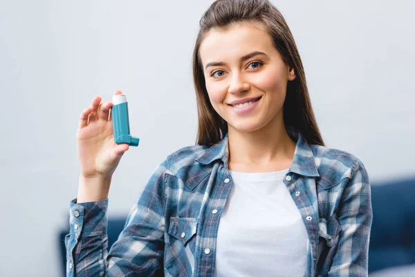 Heureuse jeune femme tenant inhalateur et souriant à la caméra — Photo de stock