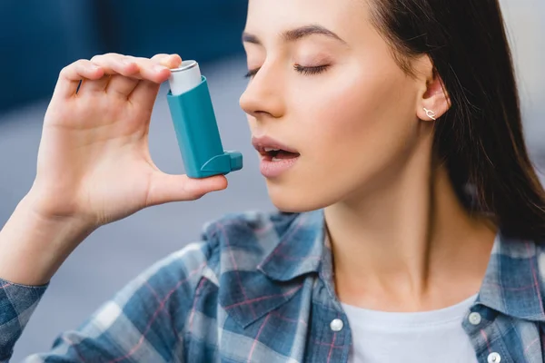 Vista de cerca de la mujer joven que usa inhalador mientras sufre de asma - foto de stock