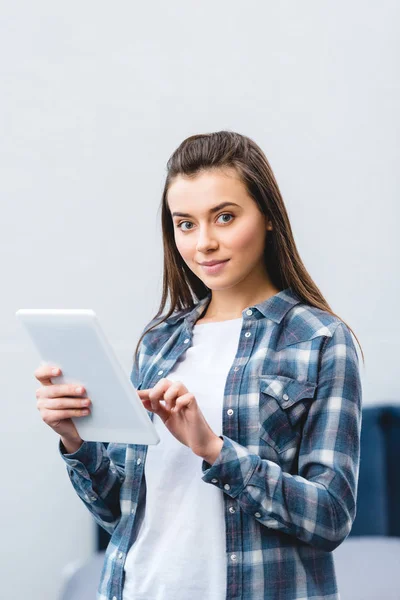 Attractive girl using digital tablet and smiling at camera — Stock Photo