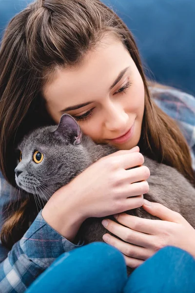 Крупный план девочки, обнимающей дома восхитительную британскую короткошерстную кошку — стоковое фото