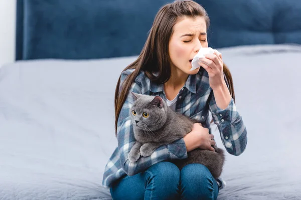 Young woman with allergy holding facial tissue and british shorthair cat at home — Stock Photo