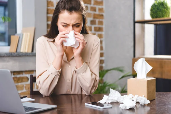 Joven empresaria con alergia en el lugar de trabajo - foto de stock