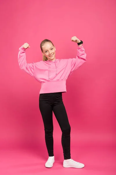 Strong athletic kid showing muscles and biceps, isolated on pink — Stock Photo