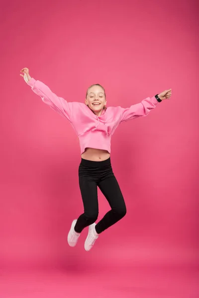Entzückendes fröhliches Kind springt isoliert auf rosa — Stockfoto
