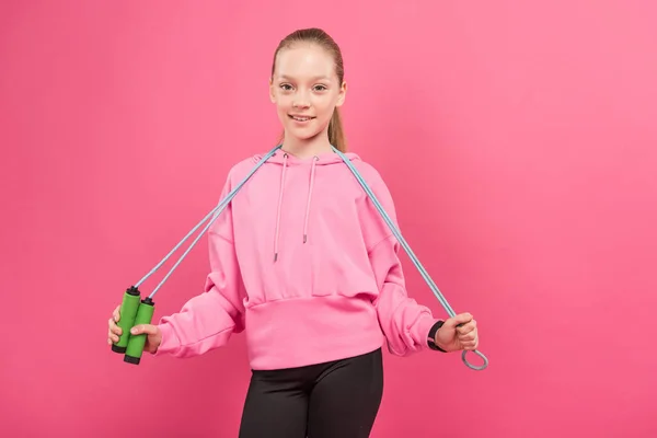 Blondes Kind in Sportkleidung mit Springseil, isoliert auf rosa — Stockfoto