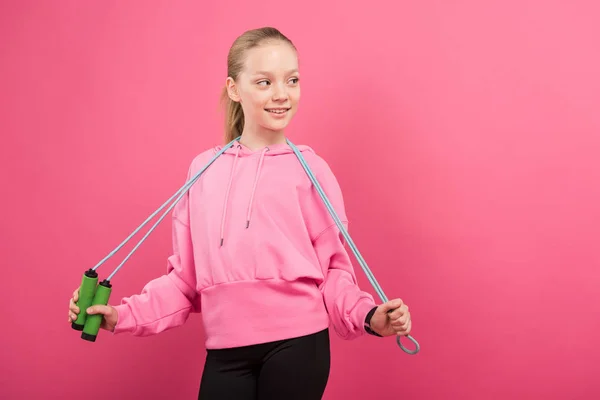 Entzückendes Kind in Sportkleidung posiert mit Springseil, isoliert auf rosa — Stockfoto