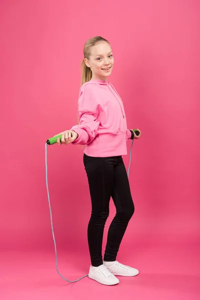 Happy child in sportswear training with skipping rope, isolated on pink — Stock Photo