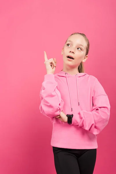 Adorable sportive kid pointing up and having idea, isolated on pink — Stock Photo