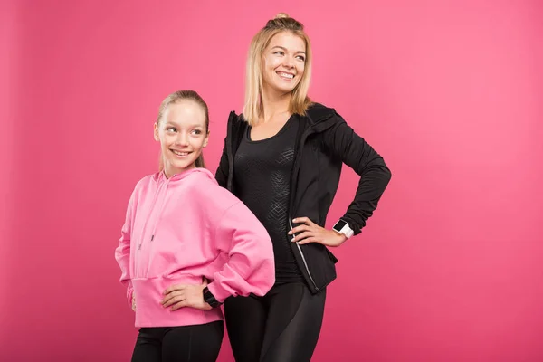 Щаслива спортивна мати і дочка позують у спортивному одязі, ізольовані на рожевому — стокове фото