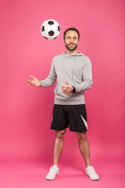 Nale Fußballspieler wirft Ball isoliert auf rosa — Stockfoto