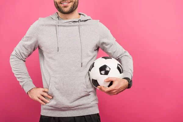 Vista recortada del jugador de fútbol sosteniendo pelota aislada en rosa - foto de stock