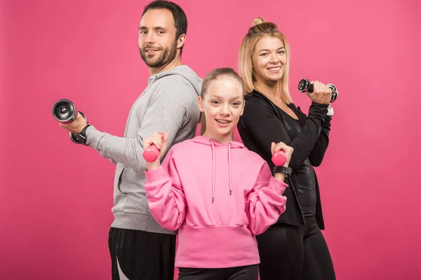 Sportive family training with dumbbells, isolated on pink — Stock Photo