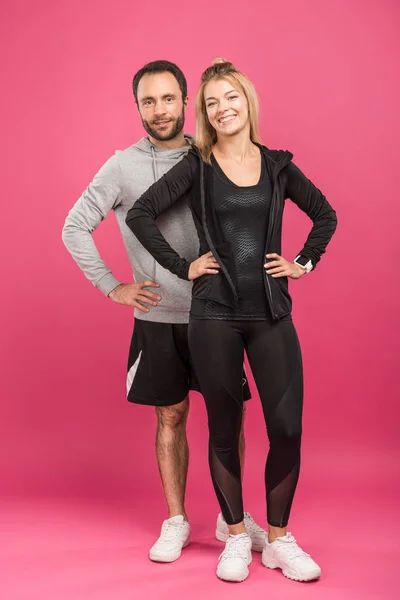 Beau couple sportif heureux posant sur rose — Photo de stock