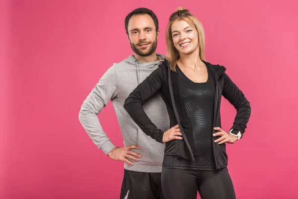Feliz pareja posando en ropa deportiva aislado en rosa - foto de stock