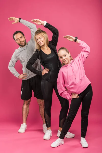 Hermosa familia atlética haciendo ejercicio en rosa - foto de stock