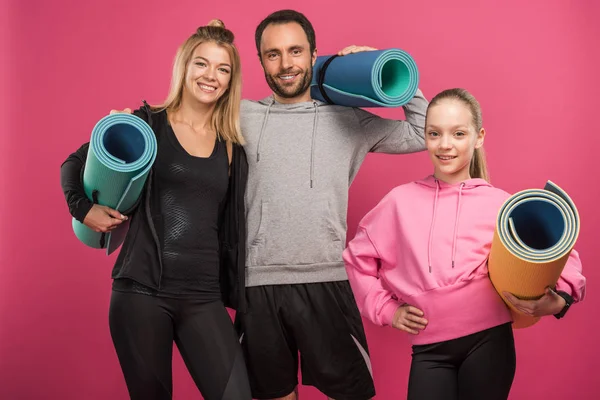 Mãe atlética, pai e filha segurando tapetes fitness, isolado em rosa — Fotografia de Stock