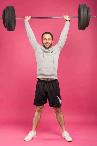 Bonito desportista formação com barbell, isolado no rosa — Fotografia de Stock