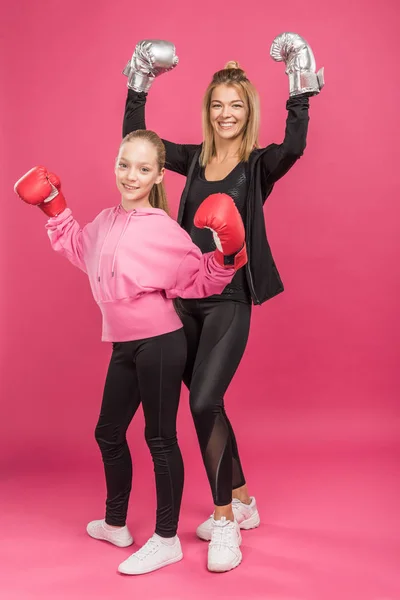 Esportivo mãe e filha posando em luvas de caixa, isolado em rosa — Fotografia de Stock