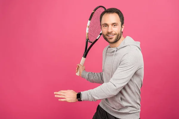 Handsome sportsman playing tennis with racket, isolated on pink — Stock Photo