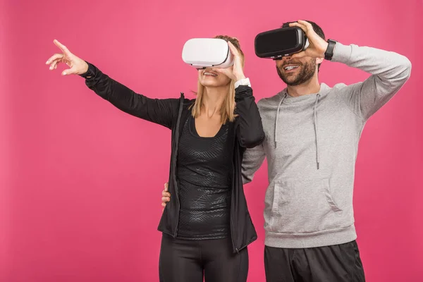 Paar gestikuliert und nutzt Virtual-Reality-Headsets, isoliert auf rosa — Stockfoto